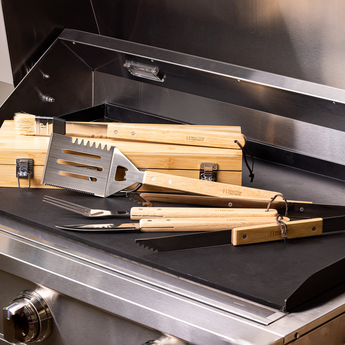 Bamboo-handled grill utensils and wooden storage case on an Induction Hardware griddle